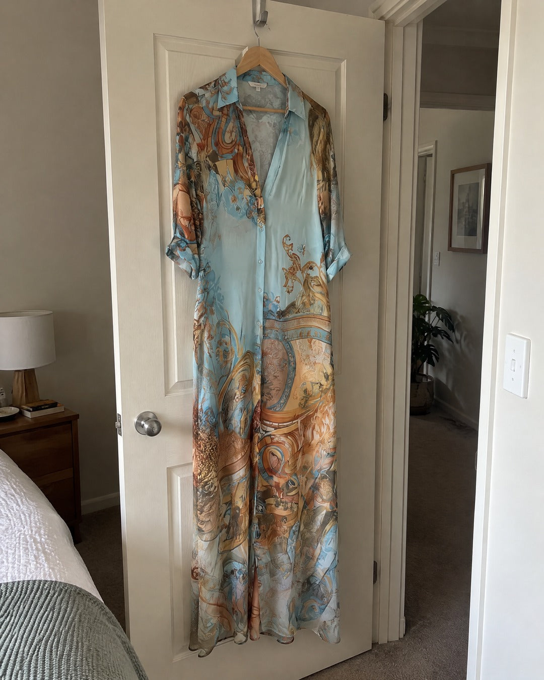Isabella blue chiffon maxi dress hanging on a bedroom door showing full length