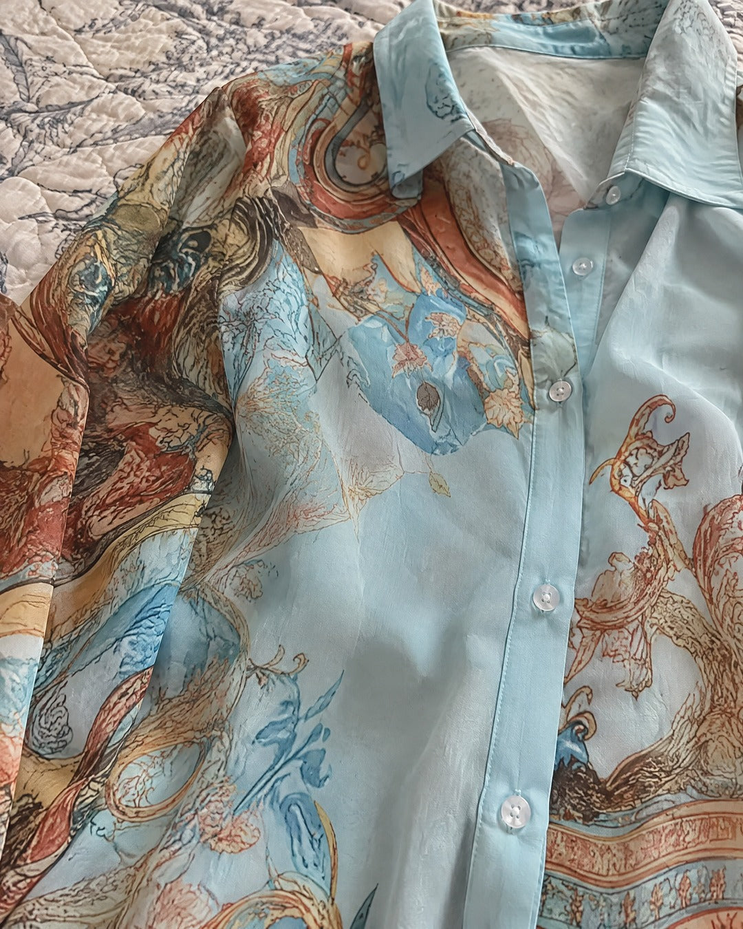 Close-up of Isabella chiffon collar button placket and ornate blue and gold print