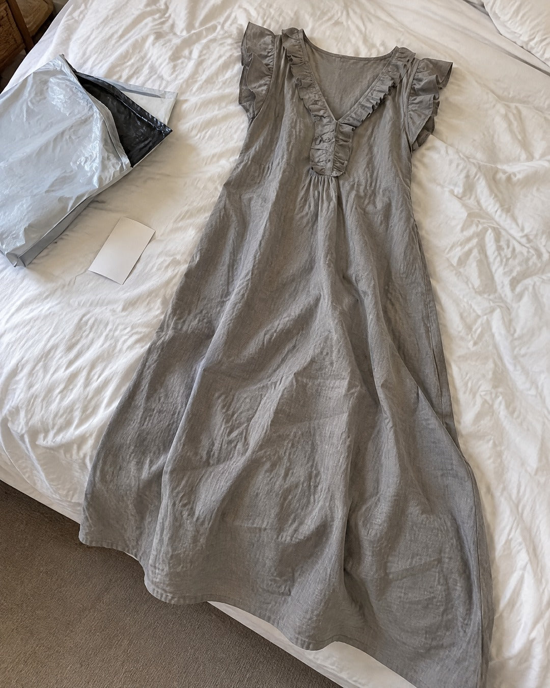 Josette grey ruffle V neck loose maxi dress laid naturally on a bed