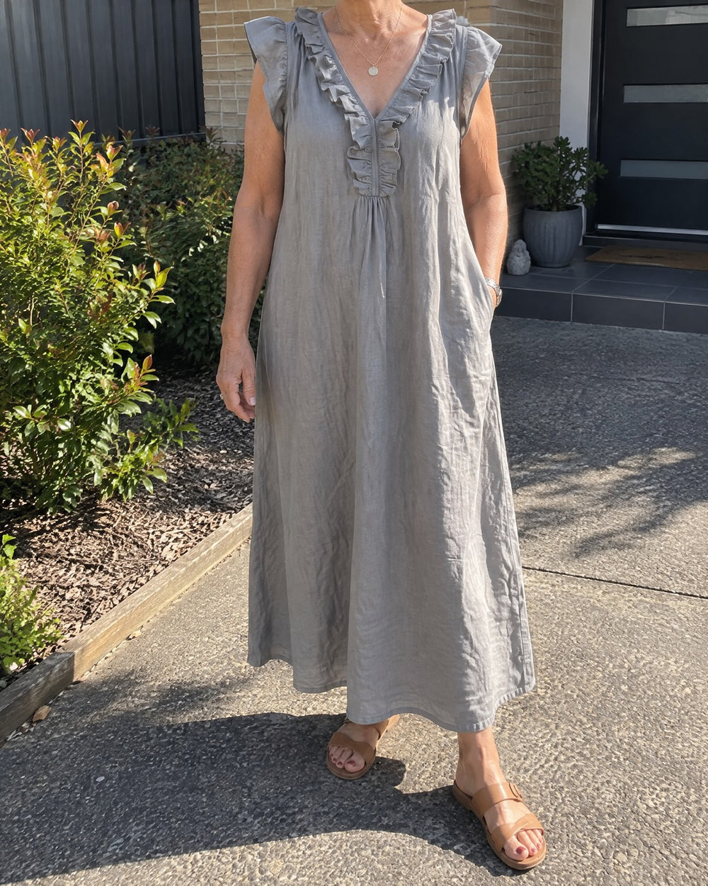 Mature woman wearing grey Josette V neck ruffle maxi dress outside a home