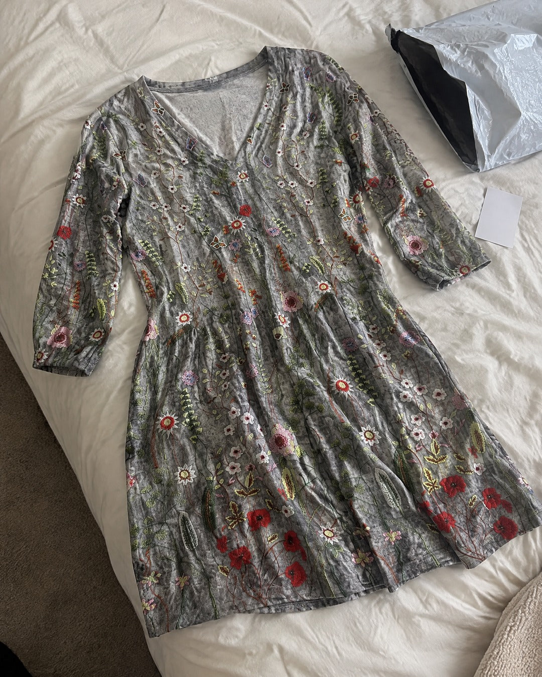 Lana long V-neck grey floral tunic laid out naturally on a bed