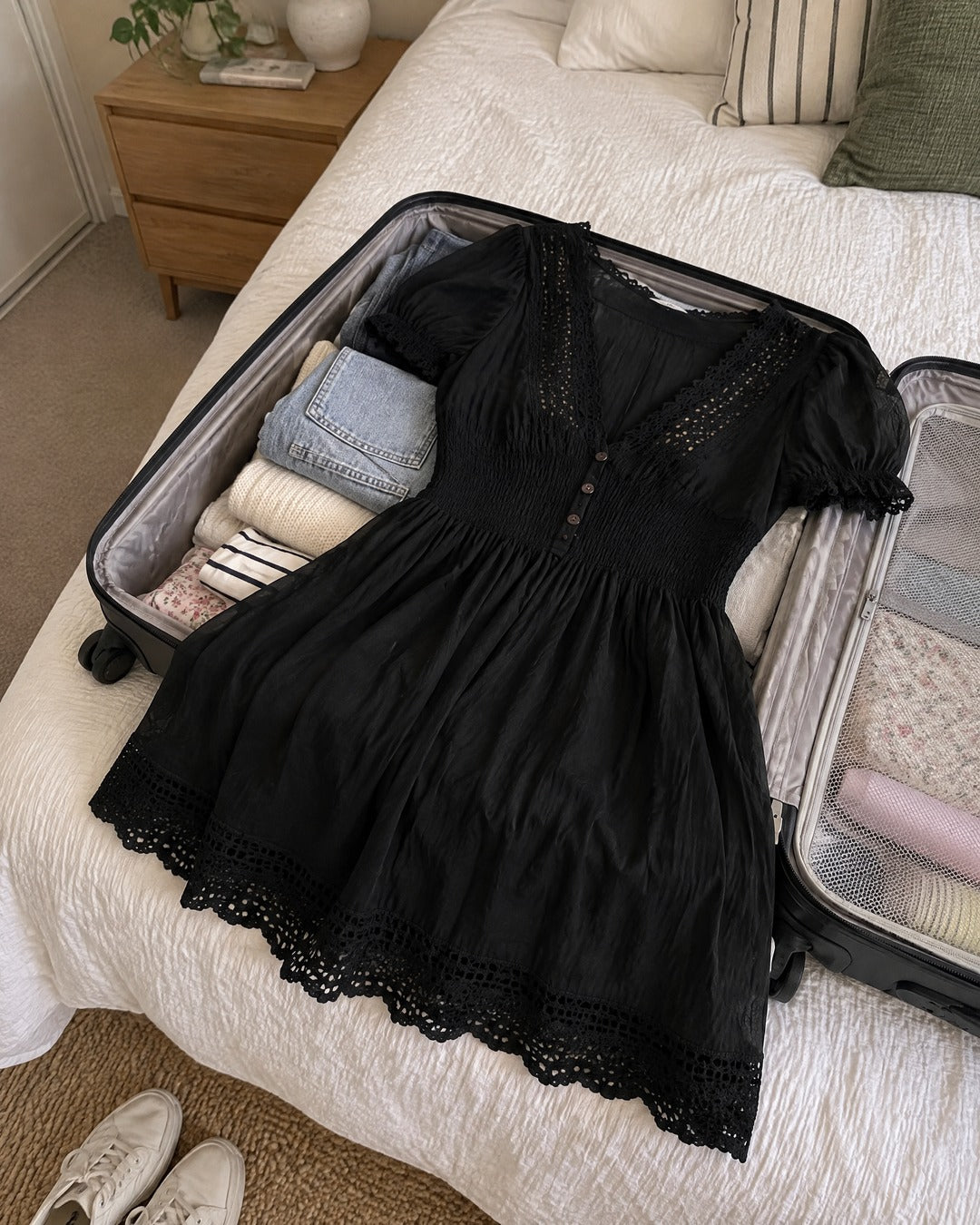 Vivienne black smocked dress being packed in an open suitcase for a trip