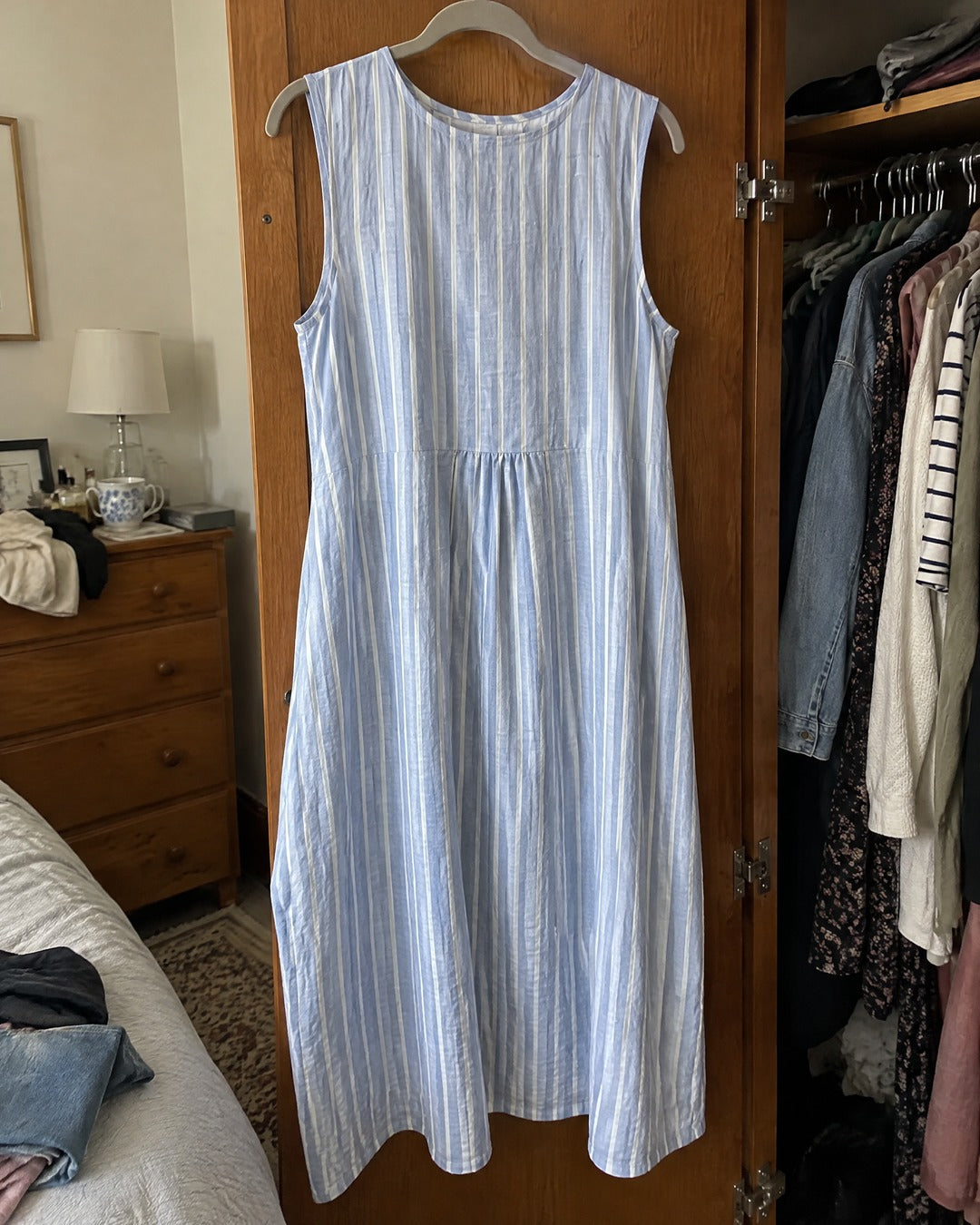 Dina blue striped midi dress hanging on a wardrobe